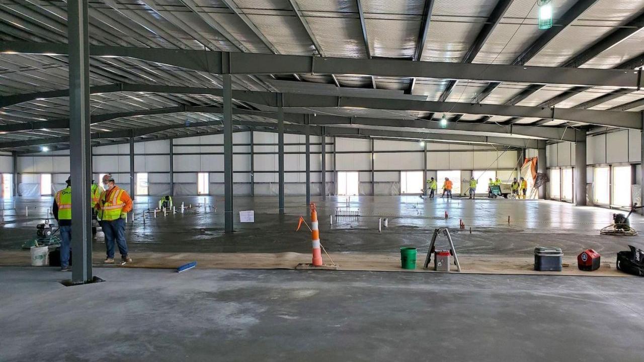 A large open building with concrete floor being poured and set.