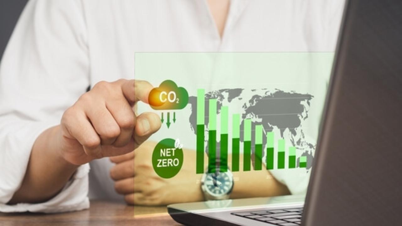Person pointing to a net-zero chart on a laptop