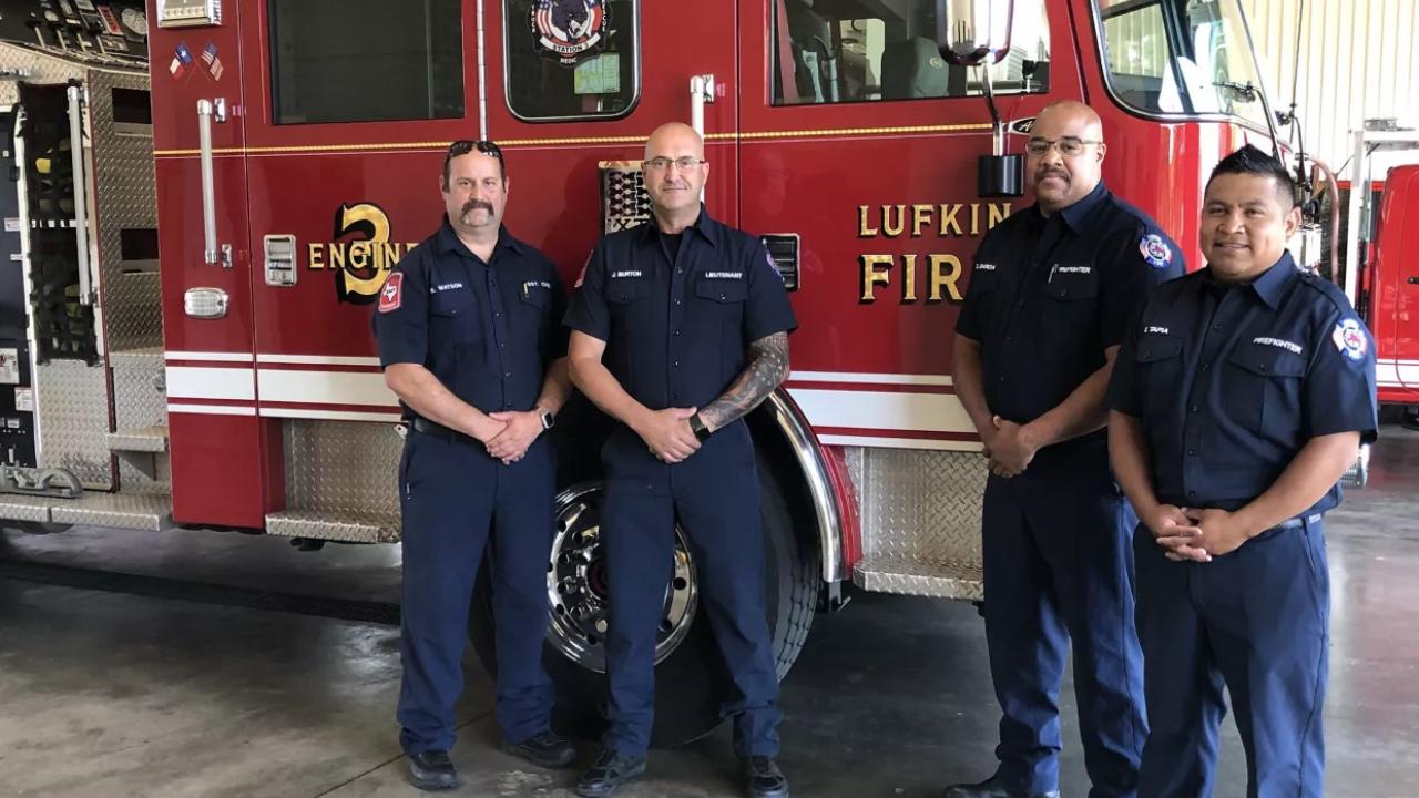 four firefighters standing by a fire truck