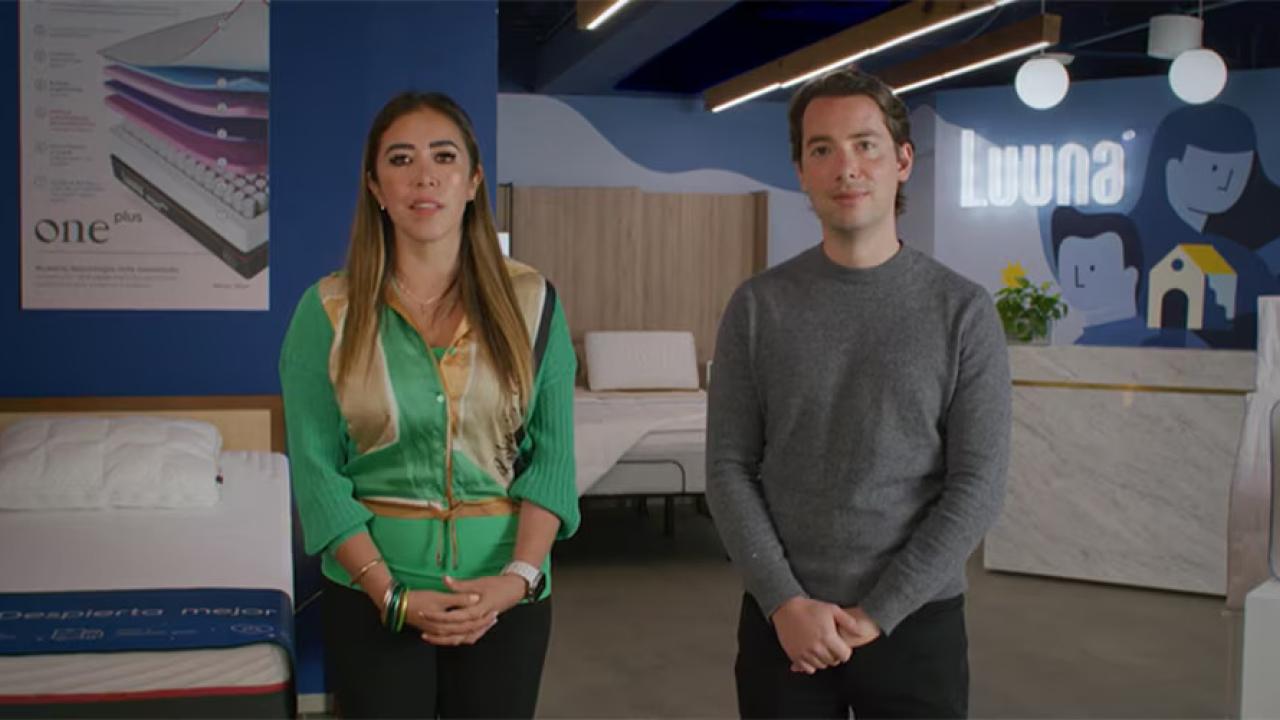 Two people standing in a mattress showroom.