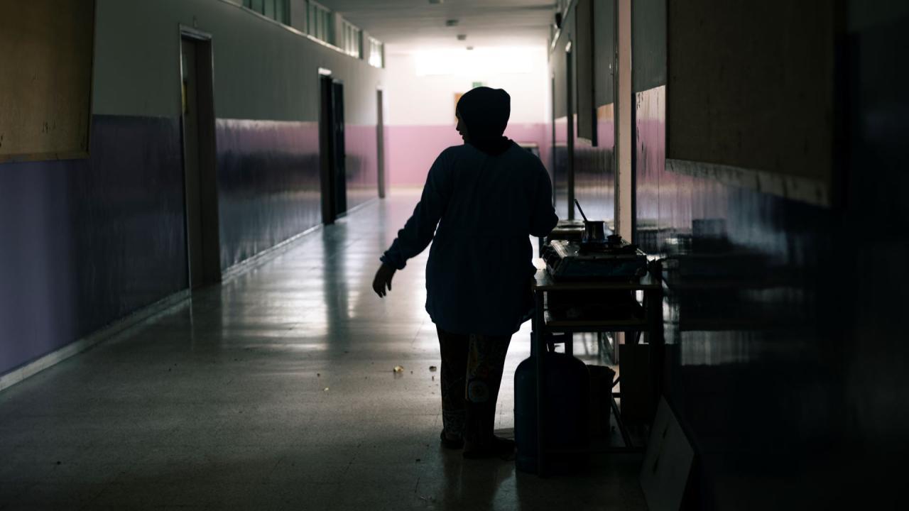 A woman cooks in one of the corridors of the Supplementary School for Girls in Tyre, Lebanon, where hundreds of people displaced by the armed conflict in southern Lebanon are sheltering. 