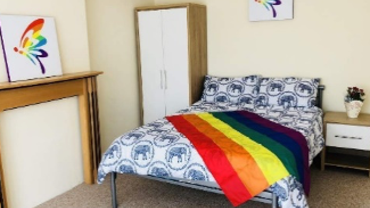 safe house bedroom with a rainbow flag on the bed and rainbow art on the walls