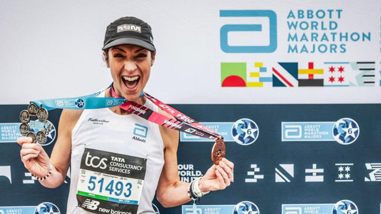 A person wearing medals in front of an Abbott World Marathon Majors back drop 
