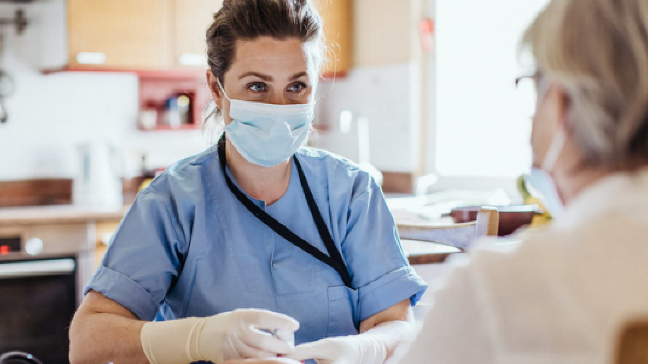 Masked person in scrubs talking to patient