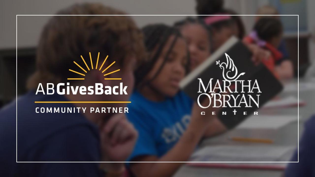 Logos for AB Gives Back and Martha O'Bryan Center over kids reading