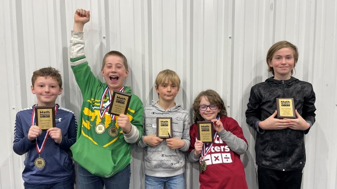 Five kids holding up math awards