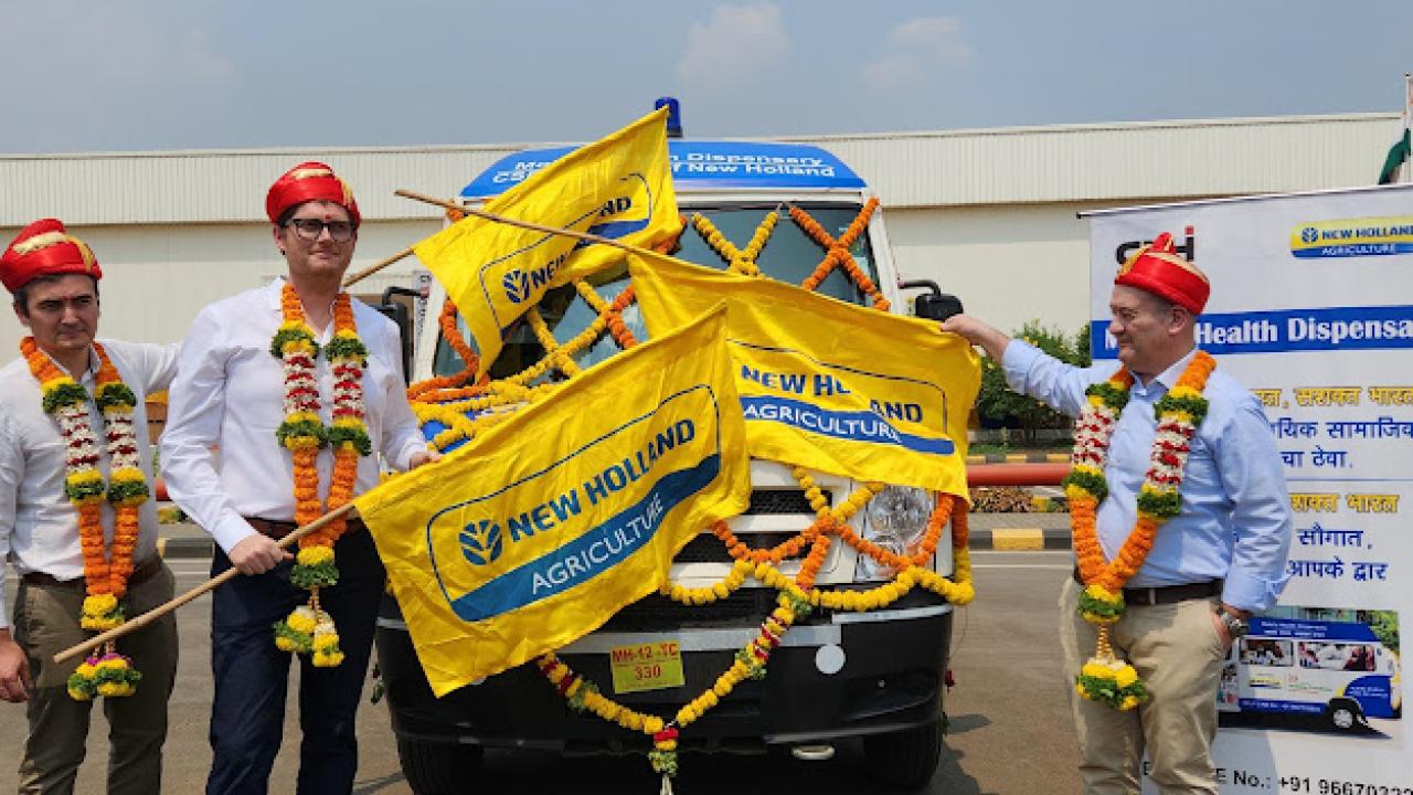 New Holland employees holding flags in front of the new mobile medical dispensary van