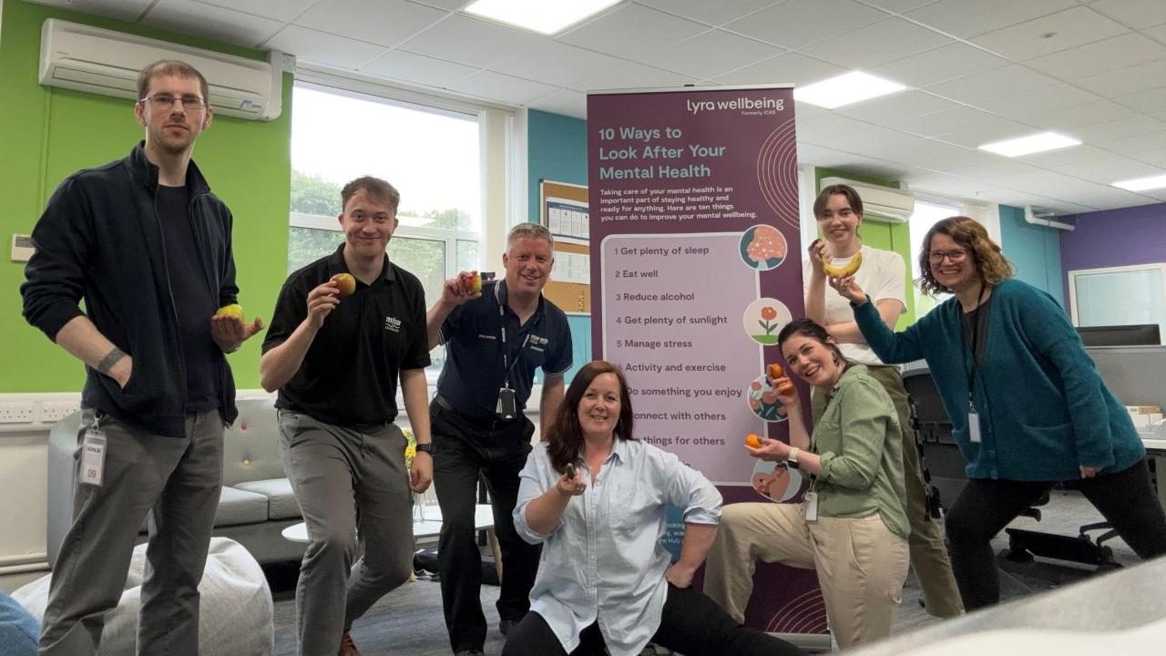 A group holding up a piece of fruit each.