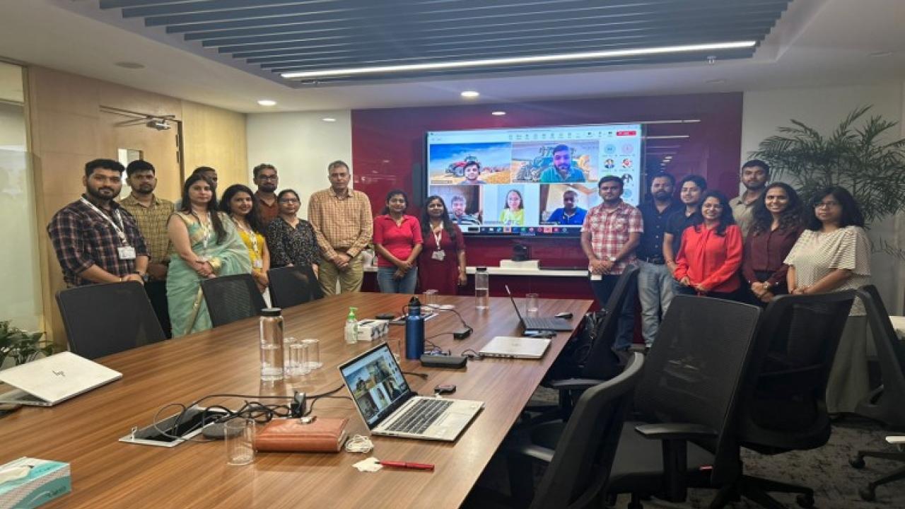 A group of people smiling and standing together in a board room in front of a large screen