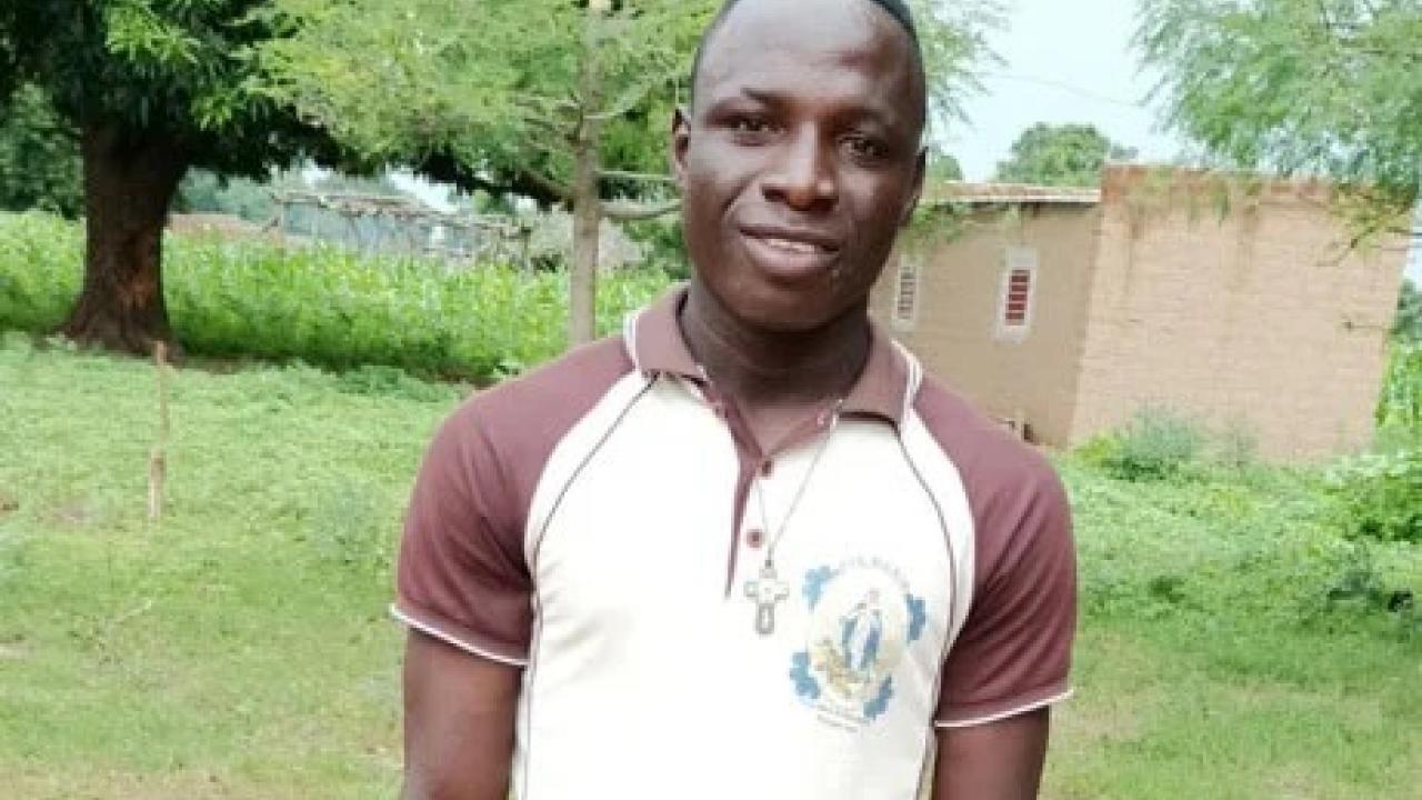 Eric in a white and brown polo shirt, standing outside