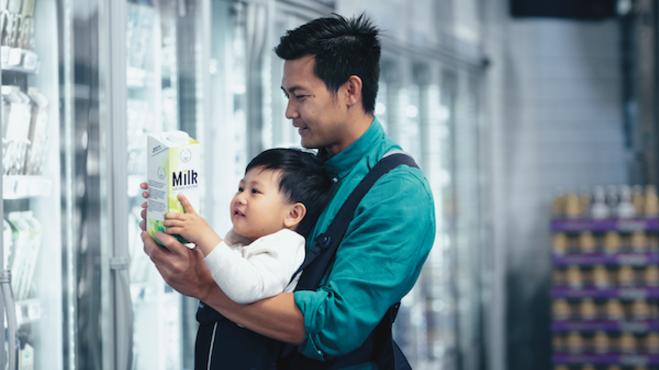Father with a baby carrier looking at milk label