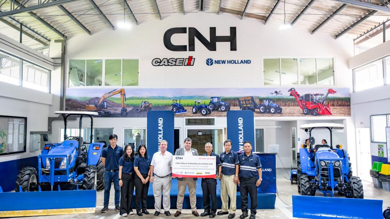 A group posed, some holding a large check, in a CNH showroom.
