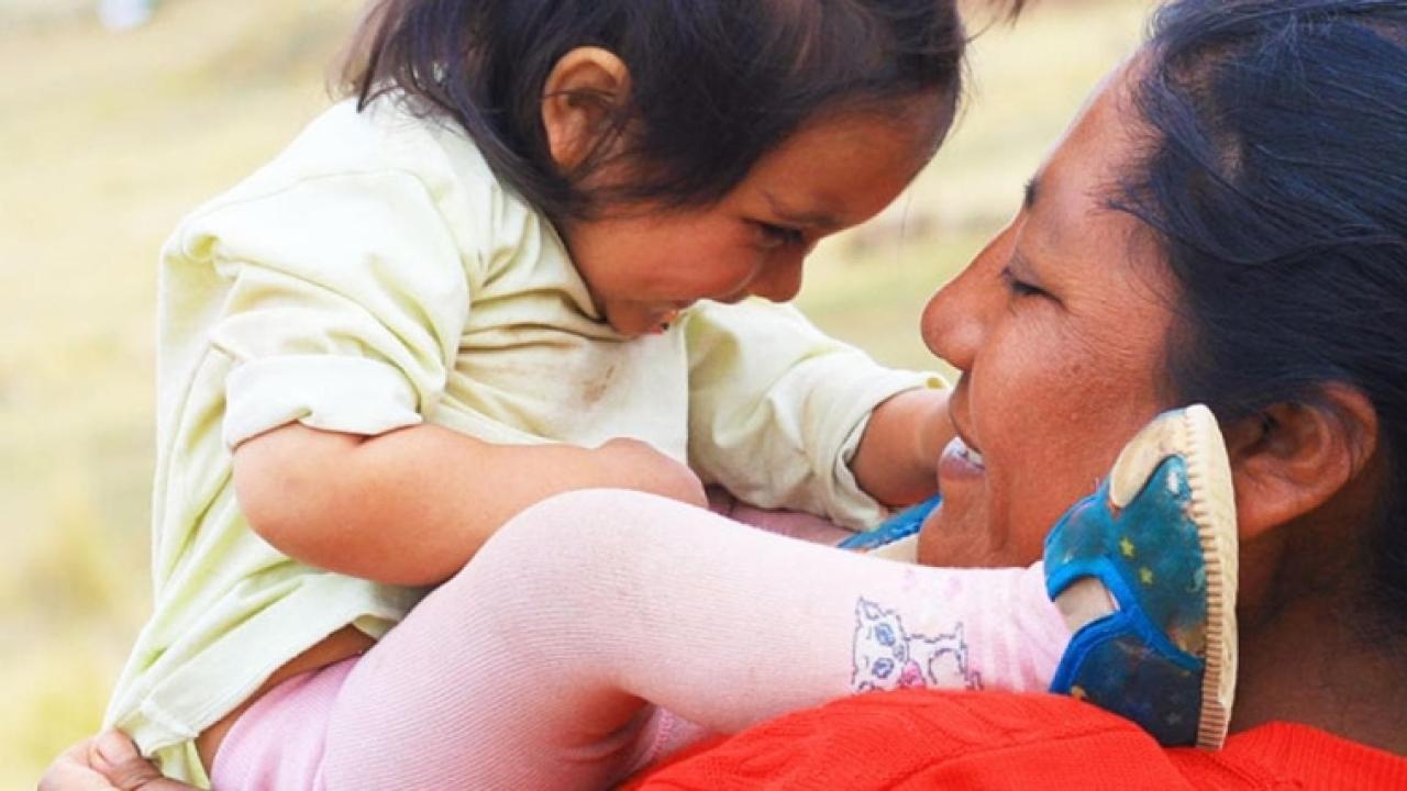 Adult holding a small child close to them, face to face