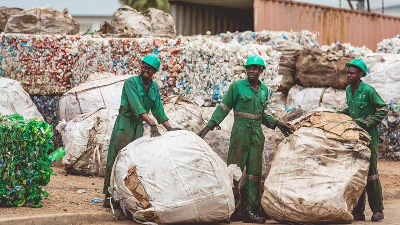 three people cleaning up plastic recycling 