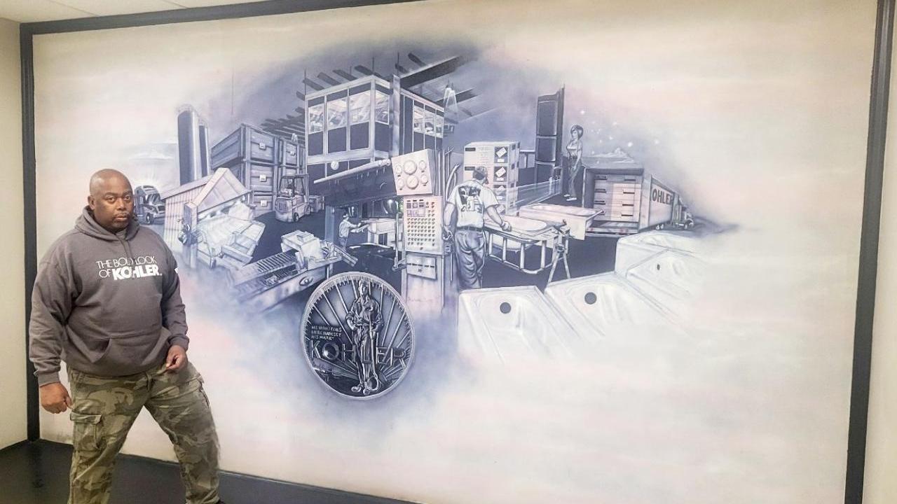 Malcolm Smith standing next to a mural on a wall.