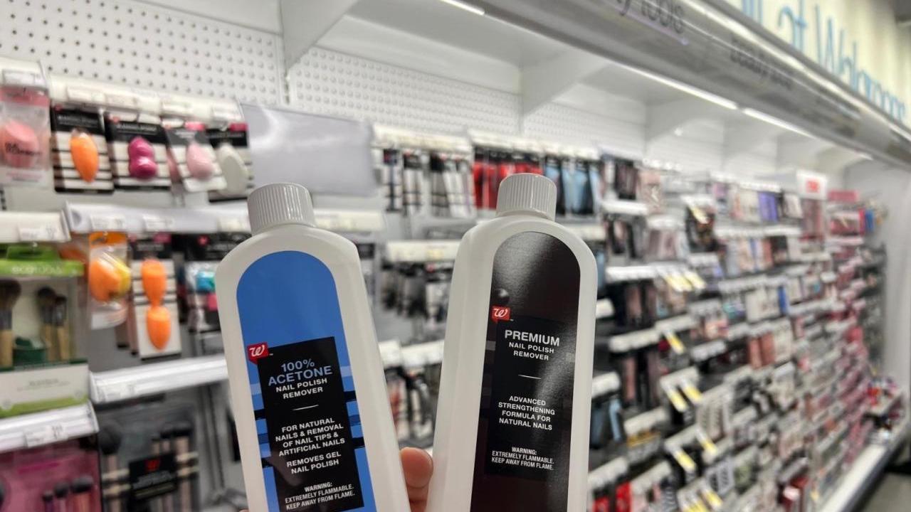 Two bottles of nail polish remover in slightly different packaging, held up in front of an aisle of beauty products.