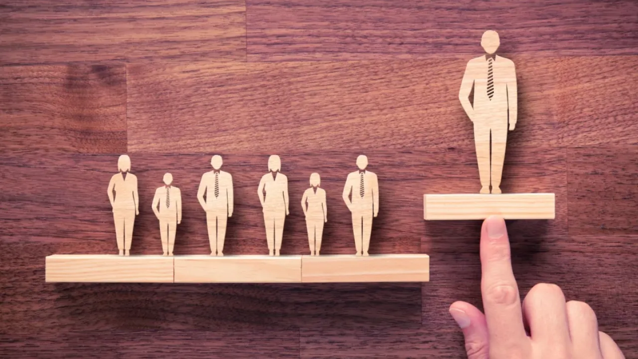 finger pointing at small wooden representation of a person
