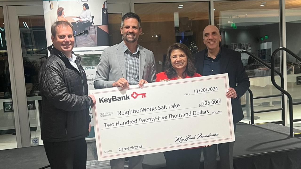 Four people holding an oversized check and smiling