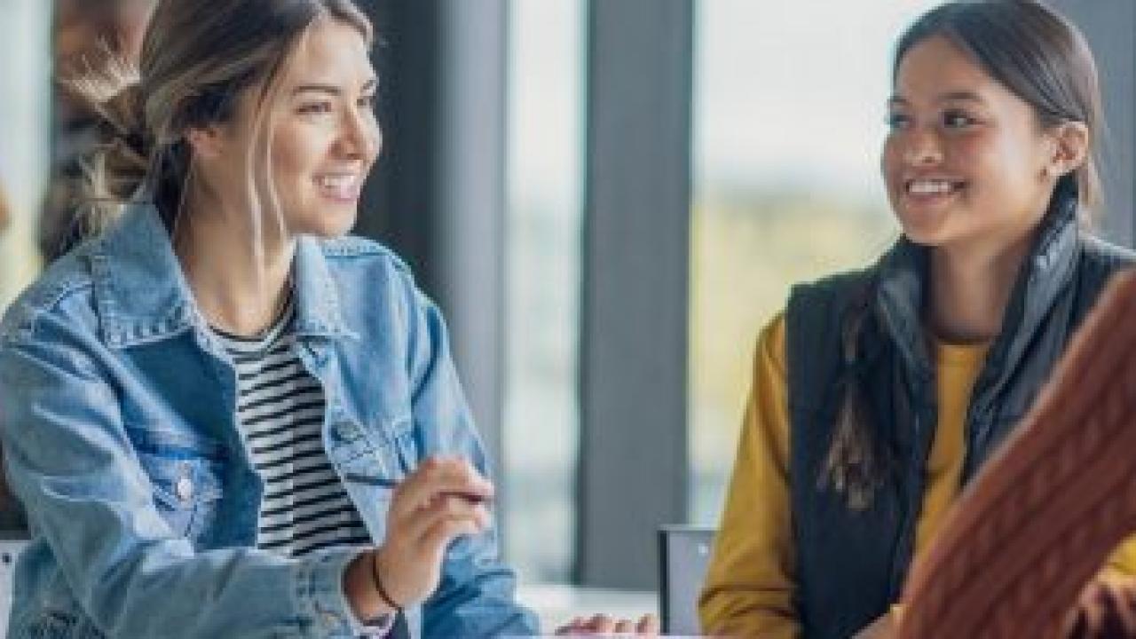 Smiling people talking at a table.