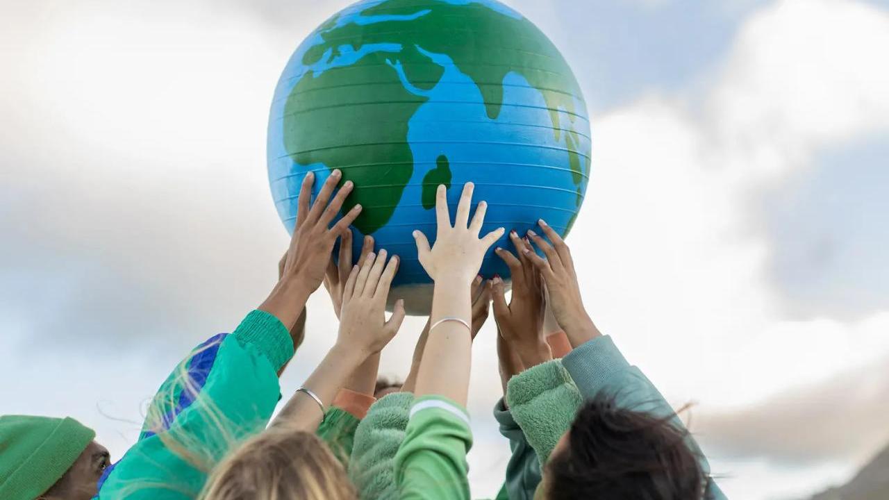 Hands holding up a globe outside