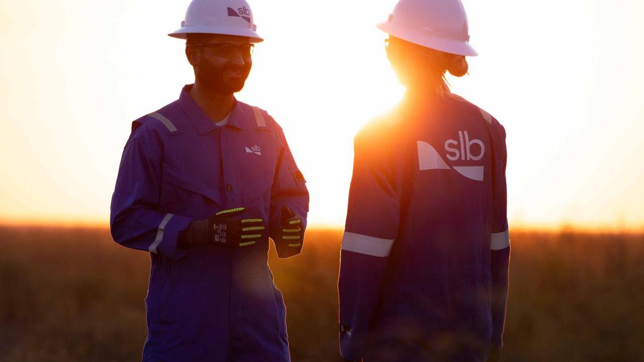 Two SLB workers talking with the sun setting behind them