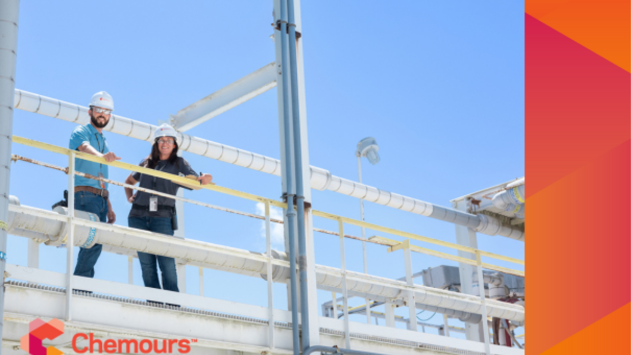 Two people in hard hats standing on a high walkway