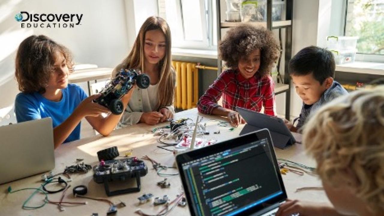 Young people work at a table on computers and electronics