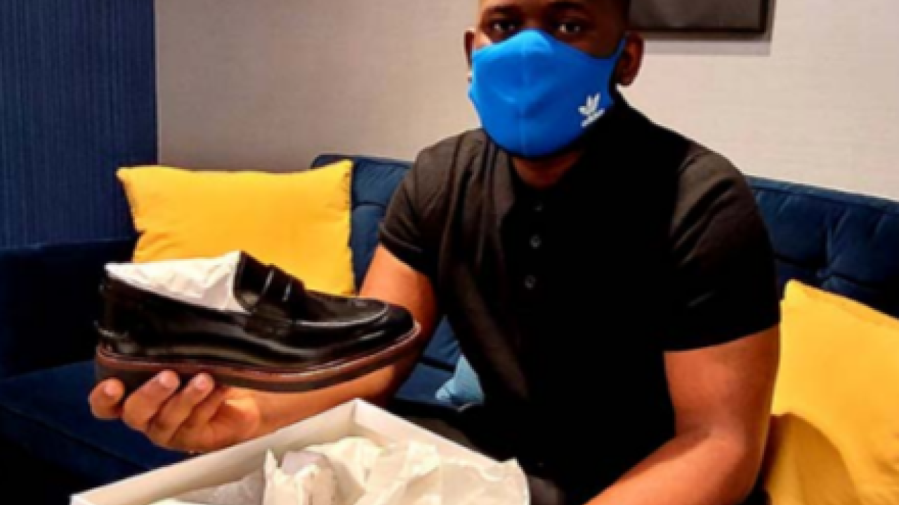 a person opens a show box holding a new black shiny work loafer