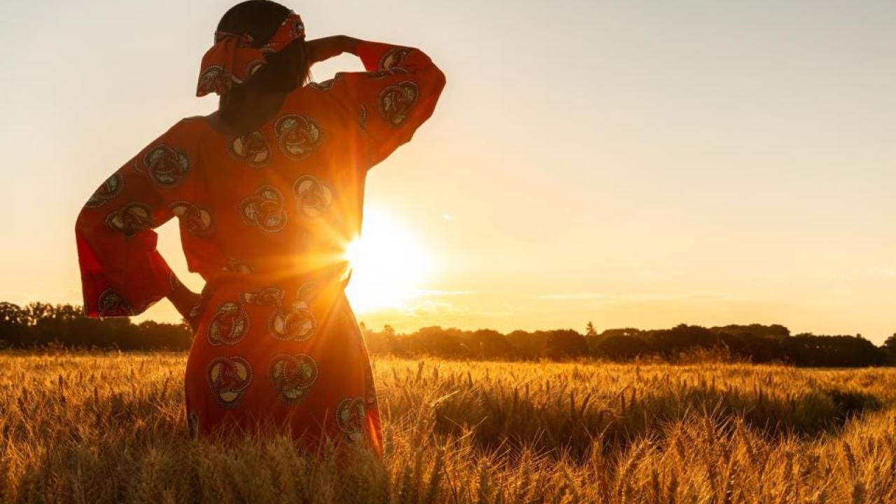 Woman in field with the sun setting