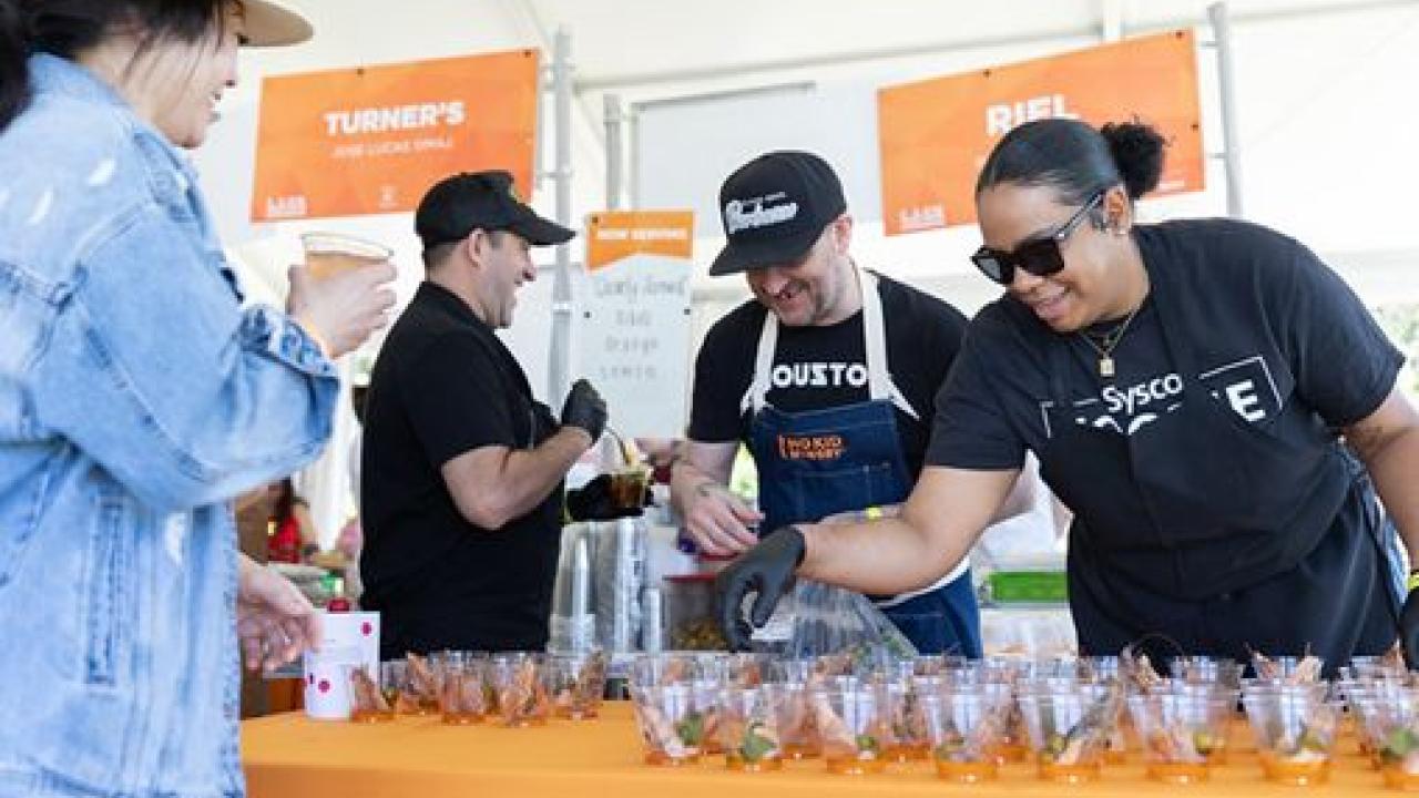 Volunteers pouring drinks on a table with an orange covering