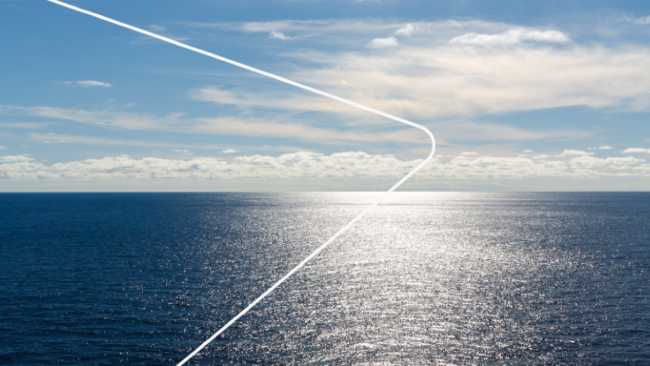 a panoramic view of open ocean. a partly cloudy sky and the sun reflecting off the water