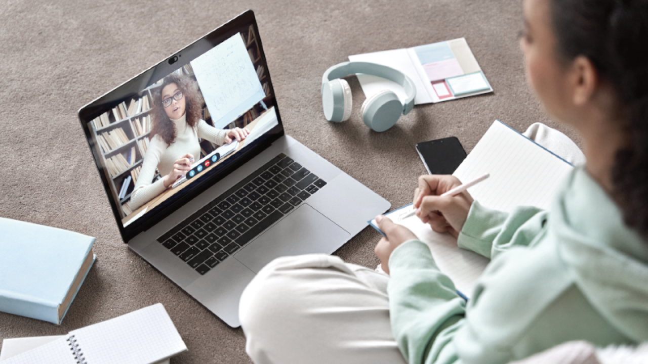 A student having an online lesson from a teacher on a laptop screen