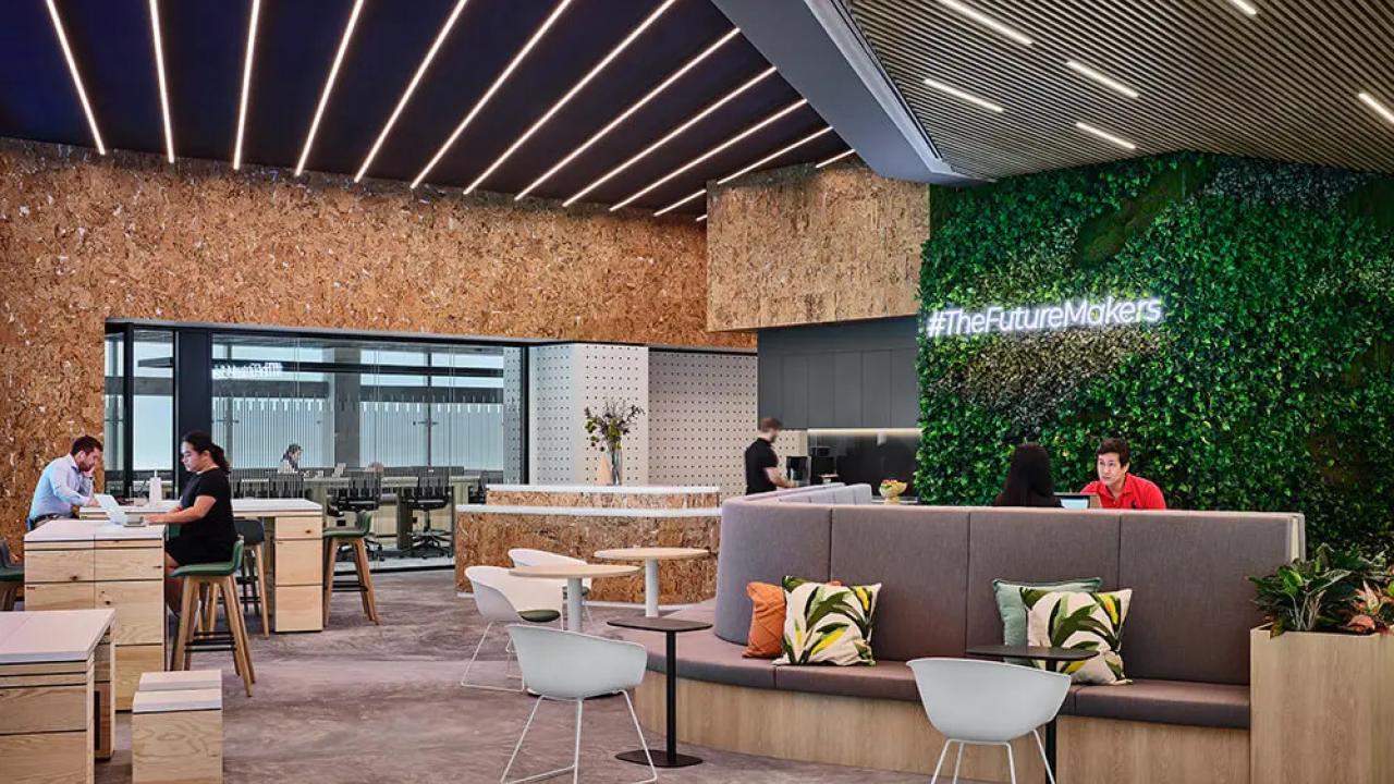 An open space with chairs, benches, carpeted floors, a wall of greenery.