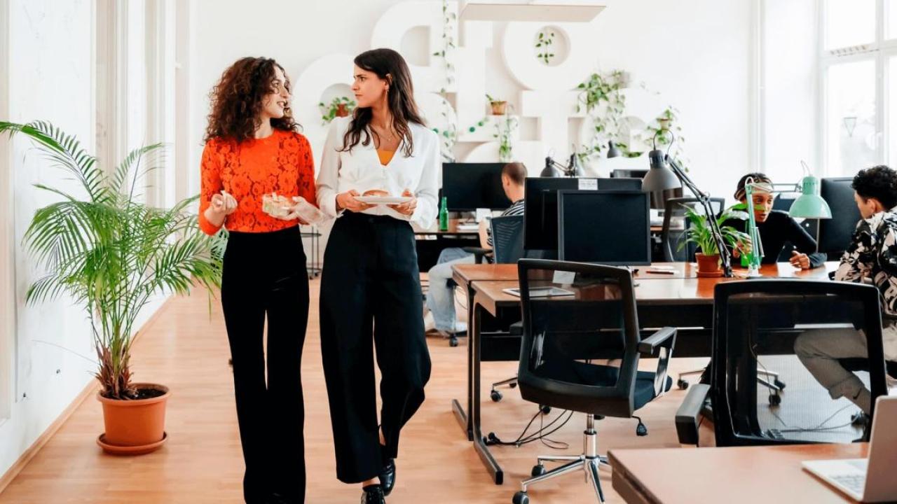 Two people walking together through an office room 