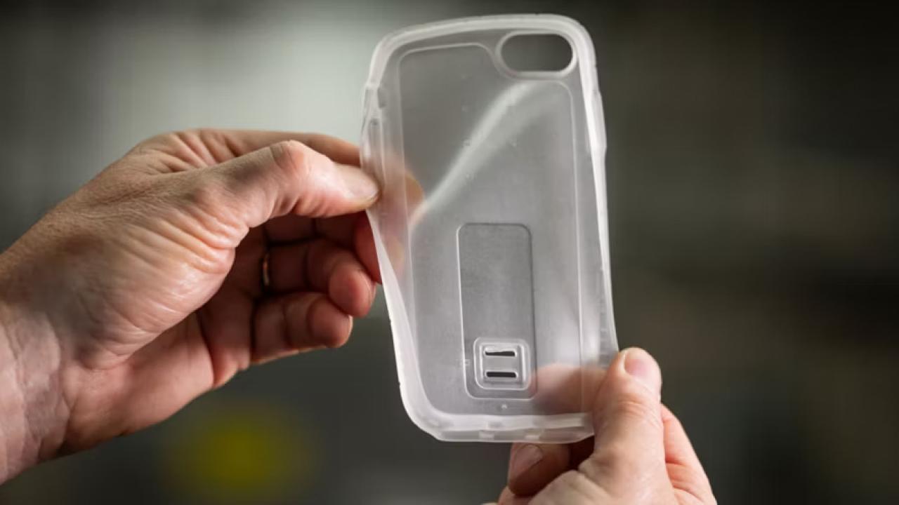 Two hands holding a clear, flexible, plastic device cover.