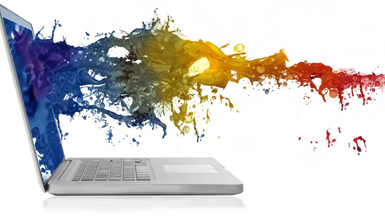A spray of multi-colored liquid splashing on a laptop screen