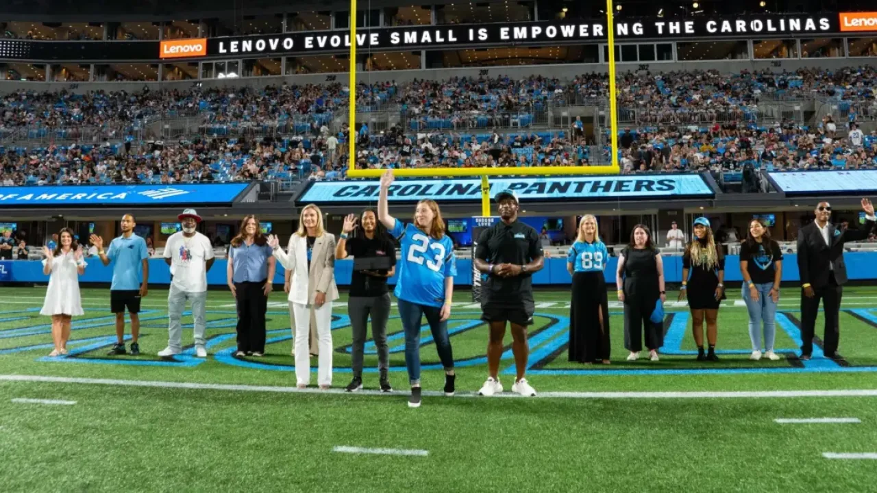 A line of people waving on a football field.