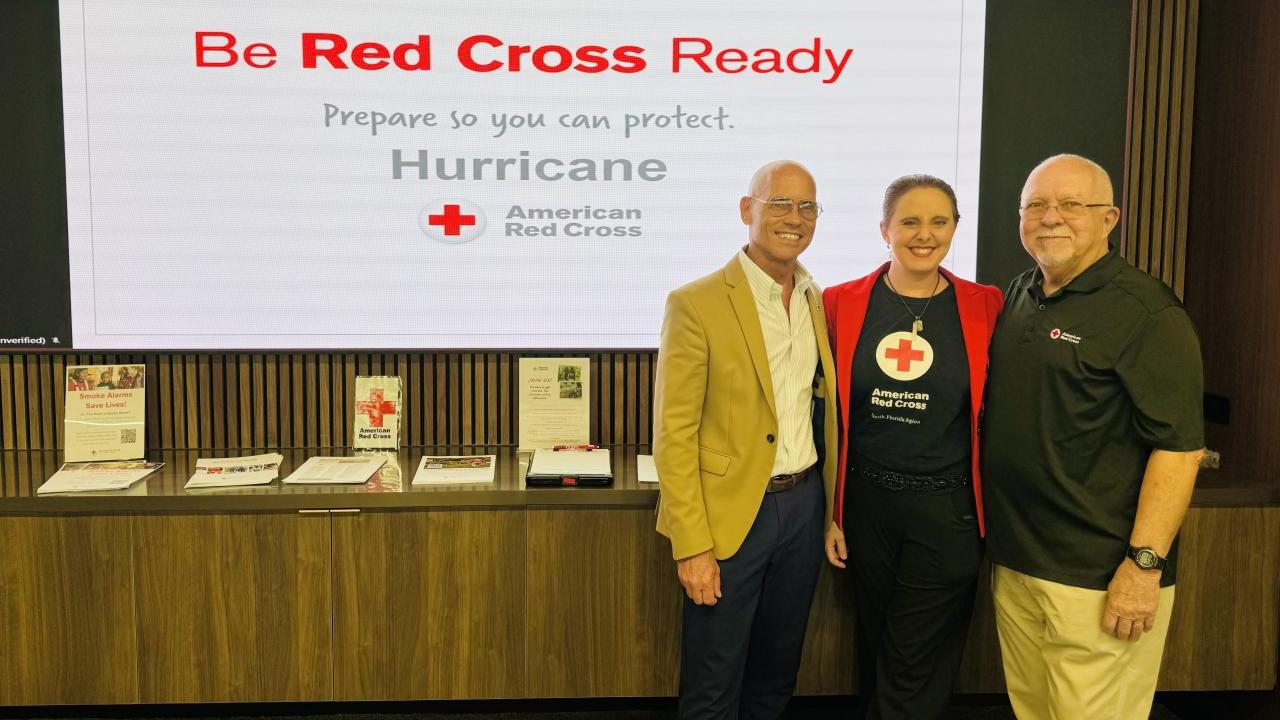 Three people standing in front of a board that reads "Be Red Cross Ready"