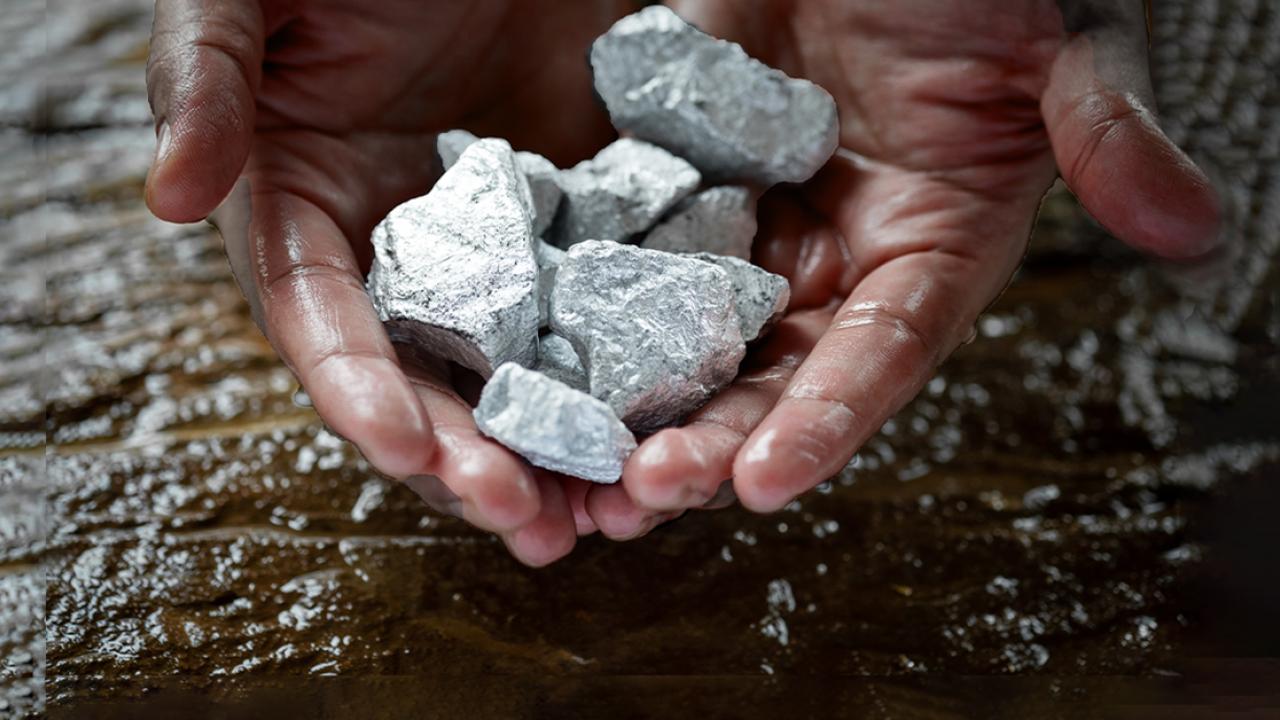 Two hands holding rocks, a wet surface underneath.
