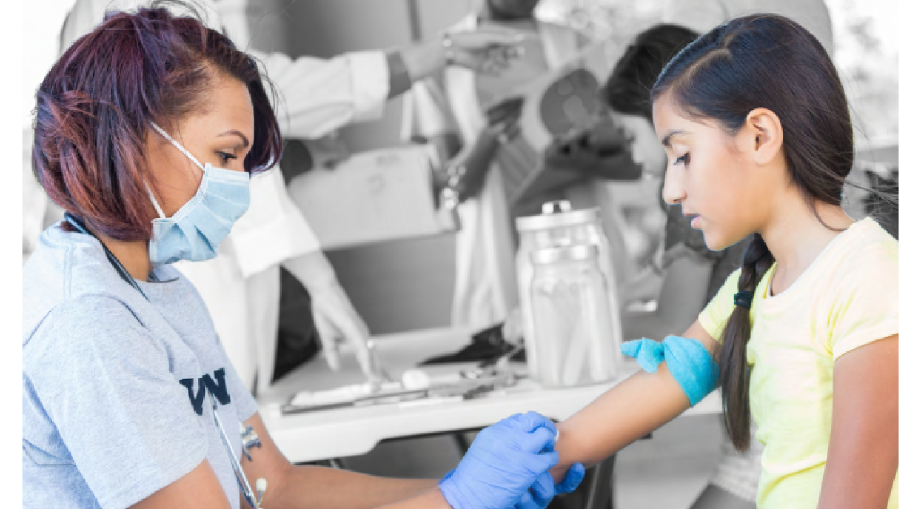 A medical provider cleans the arm of a child in a clinic setting