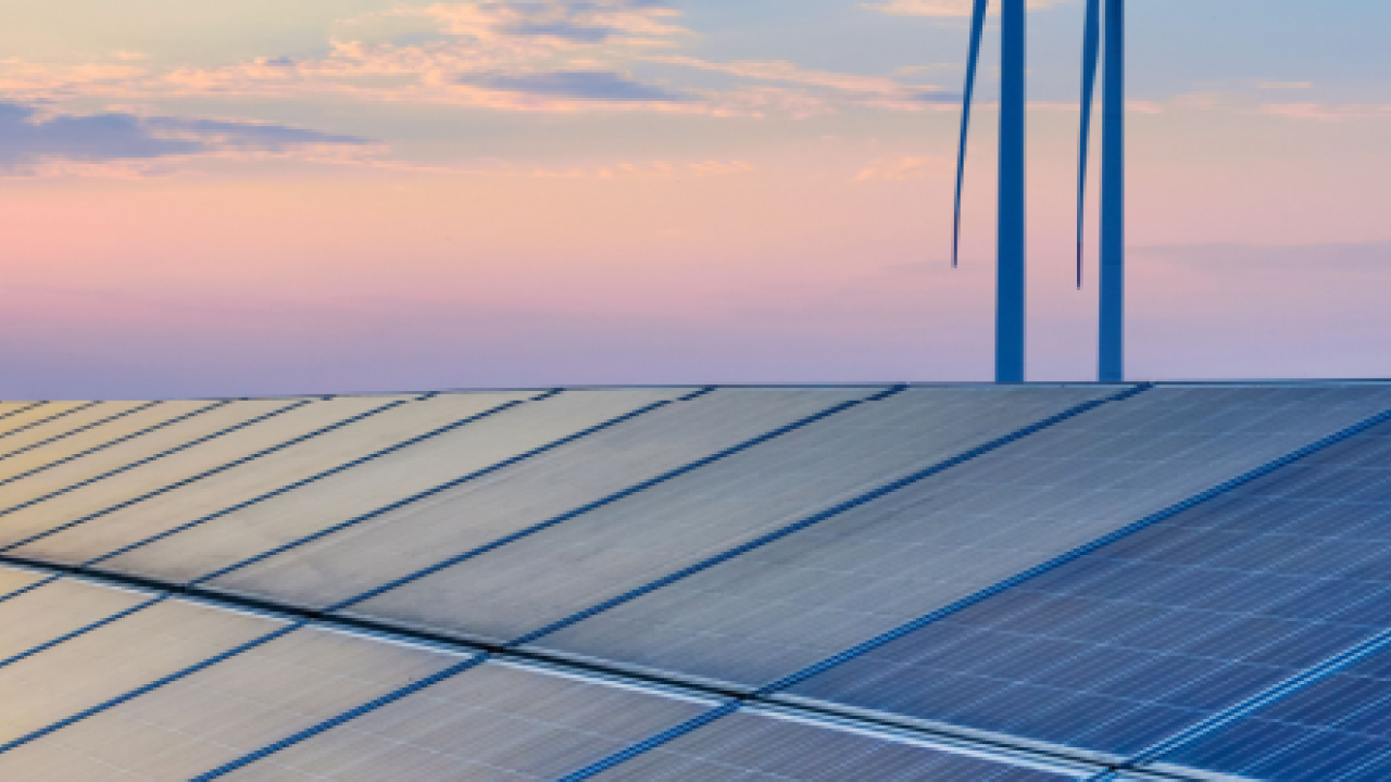 A long row of solar panels and a setting sun in the corner.
