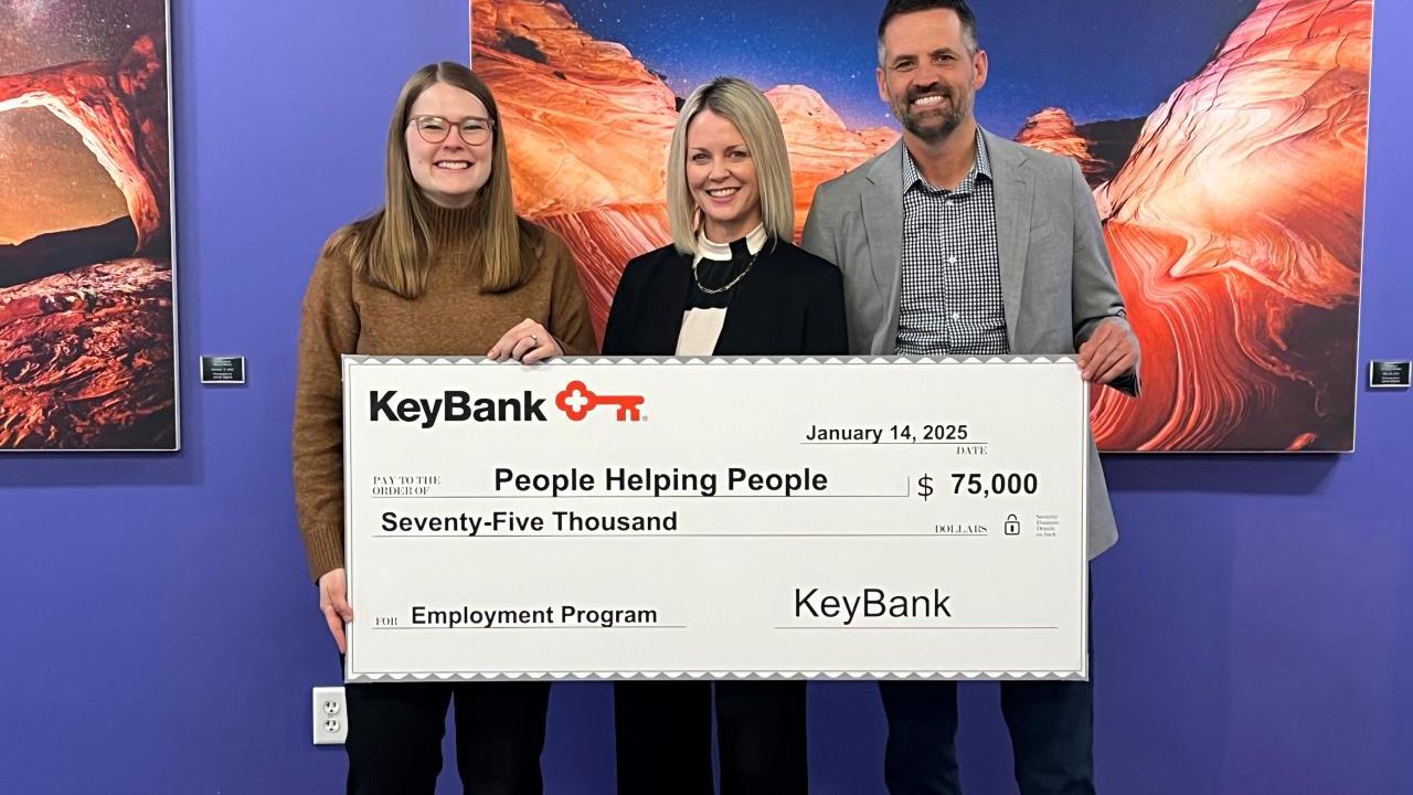 Three people holding an oversized check from KeyBank
