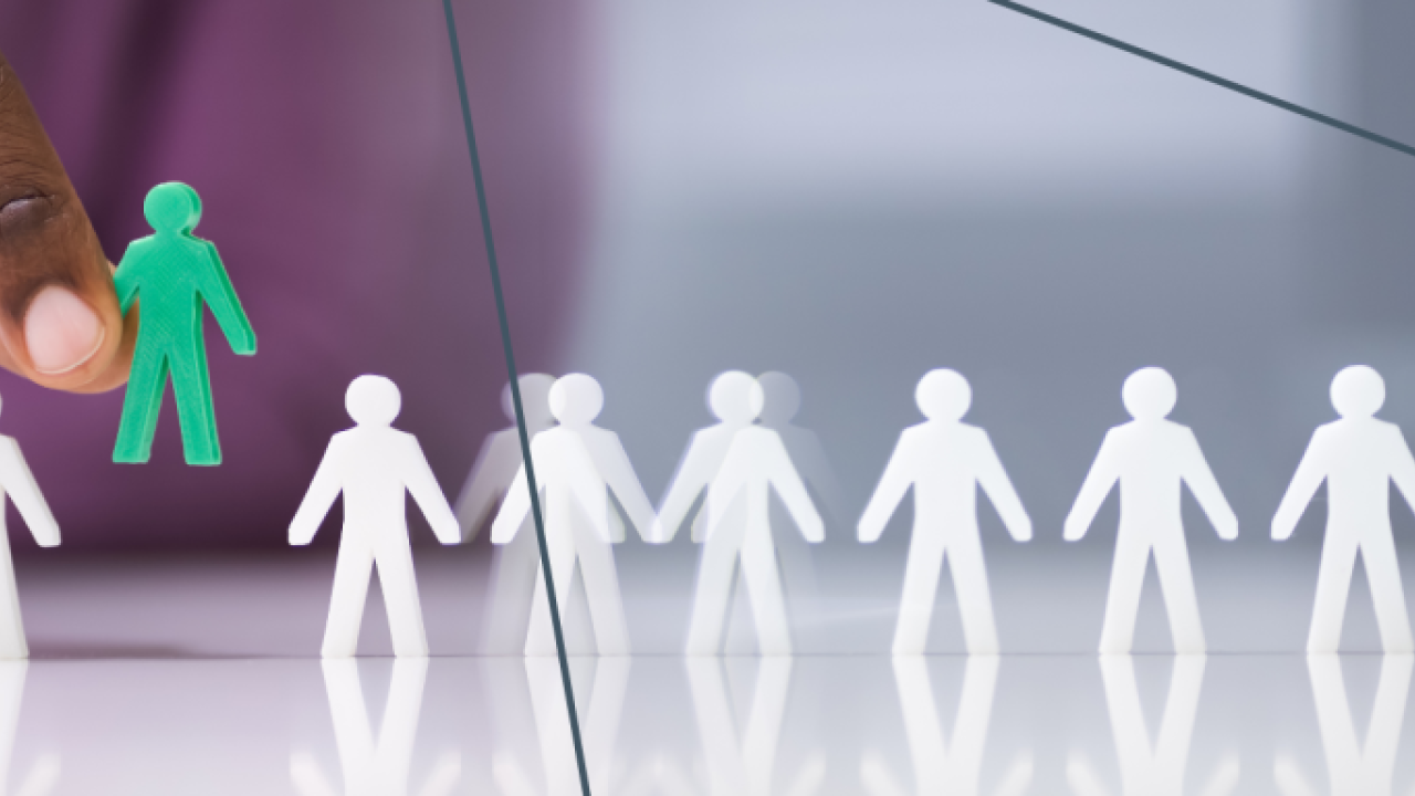 White stick figures lined up, with a green one being added 