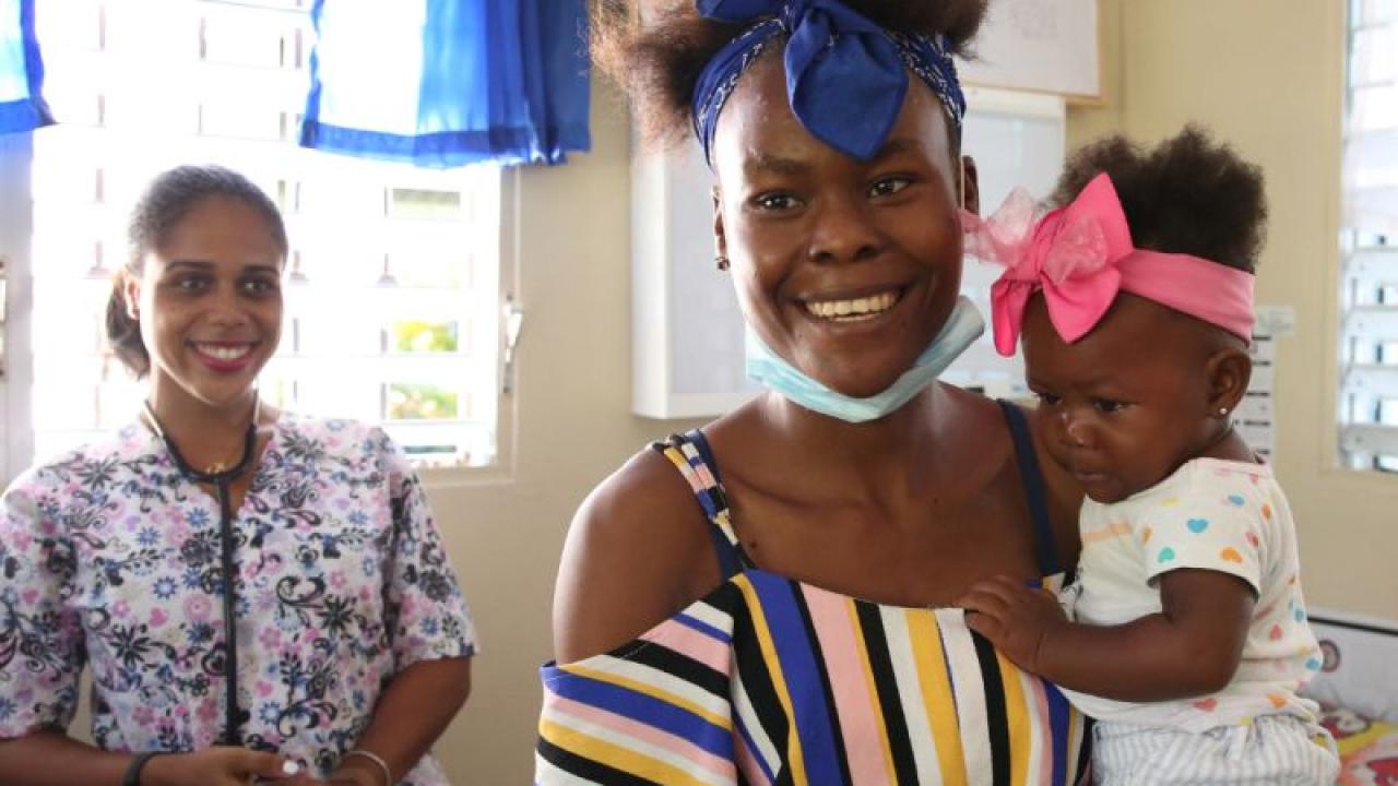 woman holding an infant and smiling