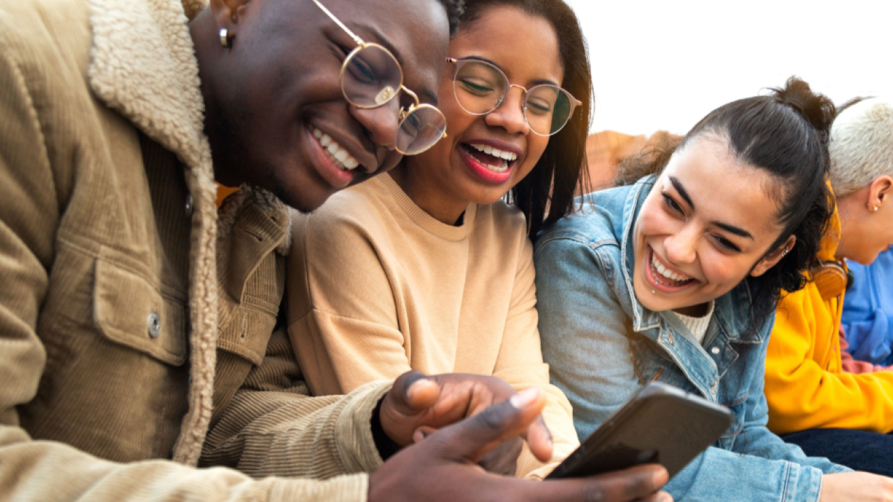 Three people look at a smartphone