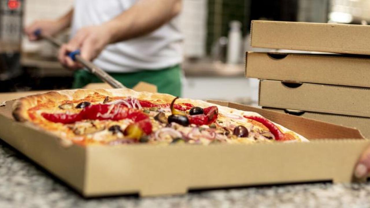 A person placing a pizza in a box.