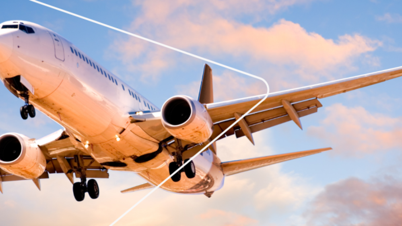 a plane in the air, clouds in a blue sky behind it