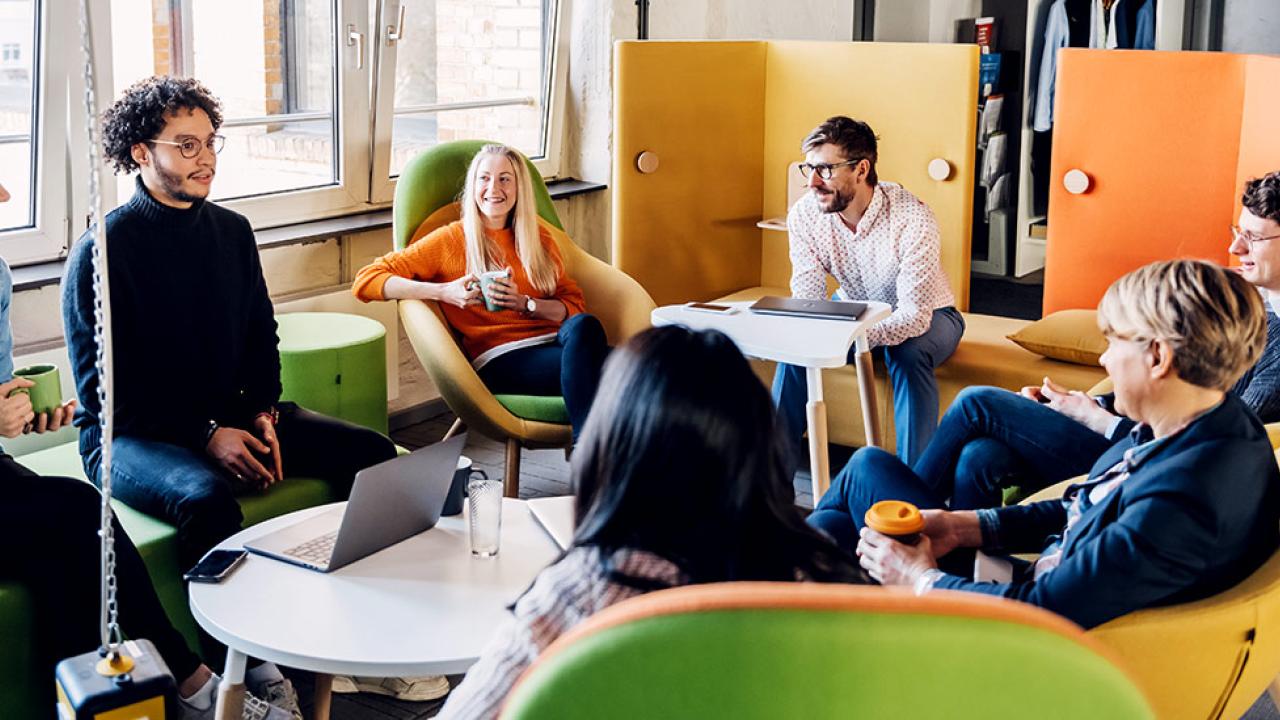 employees, sitting in brightly colored chairs, in a group conversation
