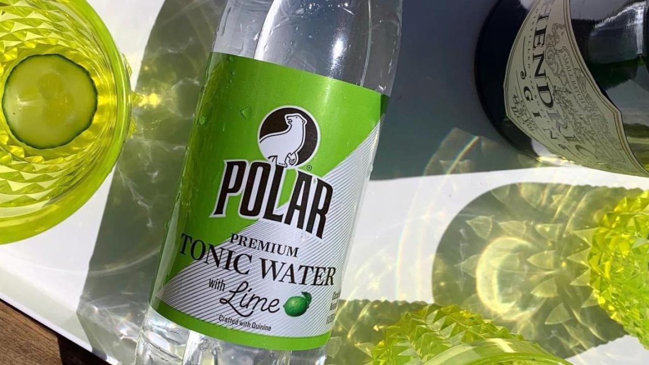 A bottle of Polar tonic water next to yellow glasses.