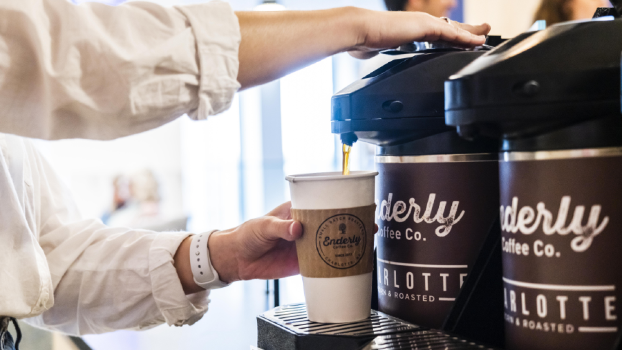 A person getting a cup of coffee from a carafe